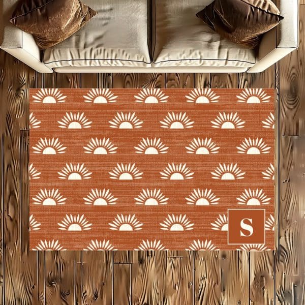 Rust-Colored Rug With A White Sun Pattern And A Monogrammed Initial.