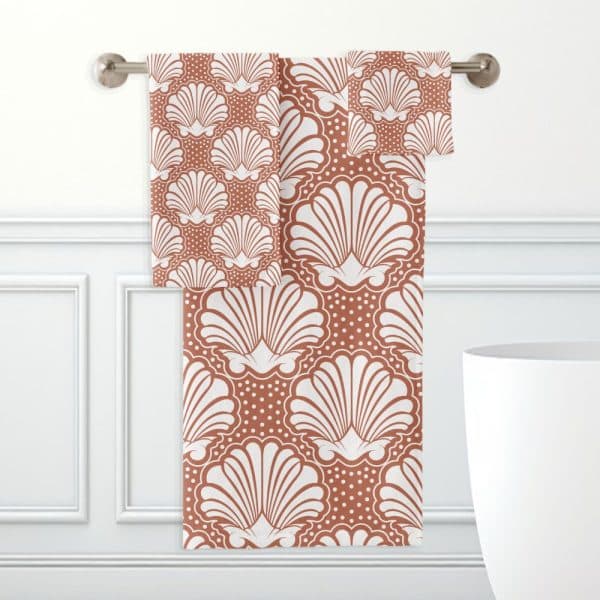 A Rust-Colored Bath Towel Set With A White Seashell Pattern.