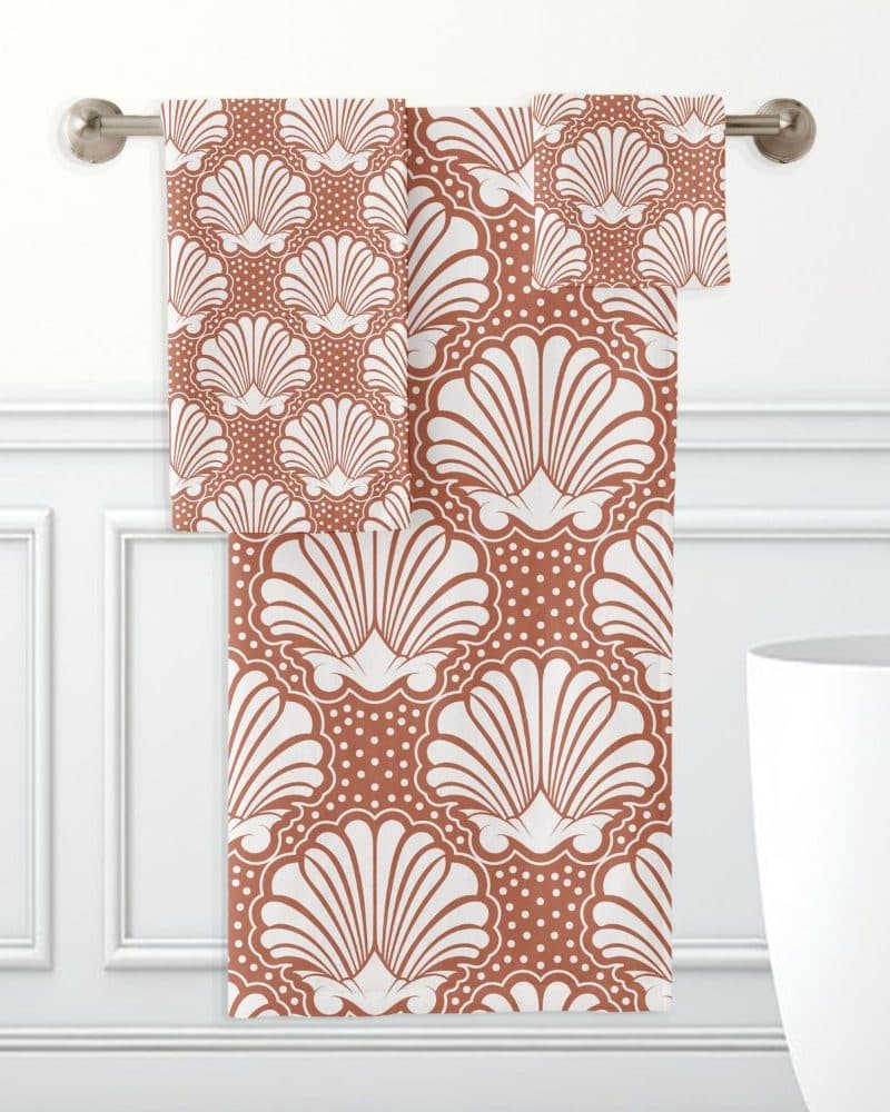 A rust-colored bath towel set with a white seashell pattern.