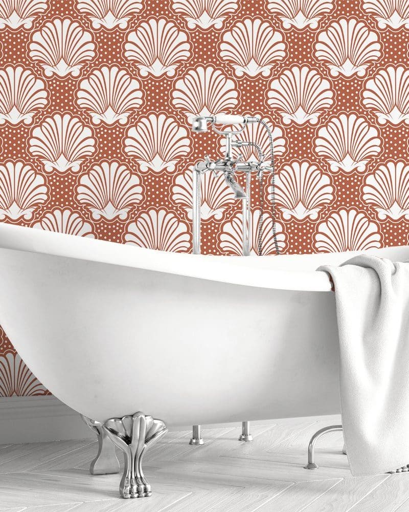 White clawfoot bathtub in front of a rust-colored wall with a white seashell pattern.