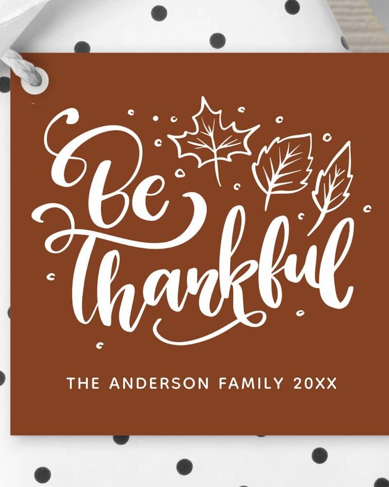 Brown gift tag with white cursive text that says Be Thankful, surrounded by simple leaf drawings. The Anderson Family 20XX is printed at the bottom.