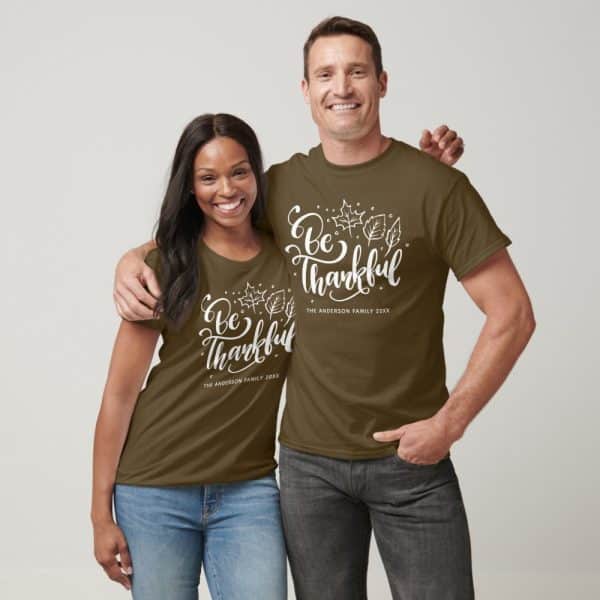 Couple Wearing Matching Olive Green T-Shirts With &Quot;Be Thankful&Quot; And Their Last Name.