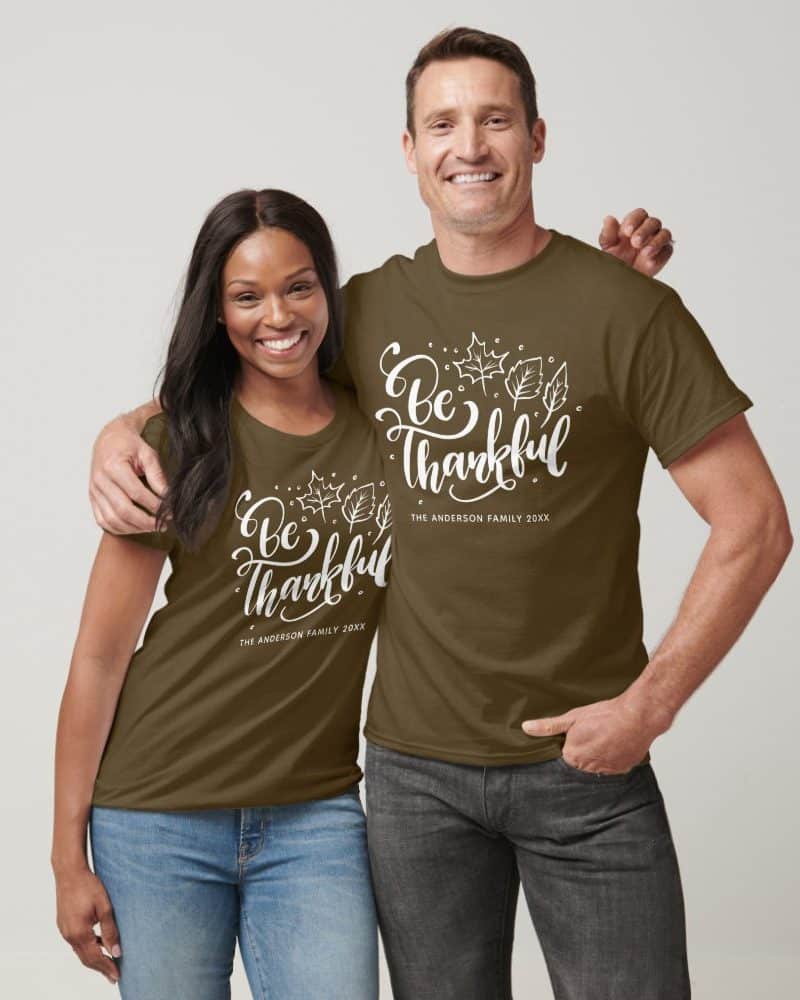 Couple wearing matching olive green t-shirts with "Be Thankful" and their last name.