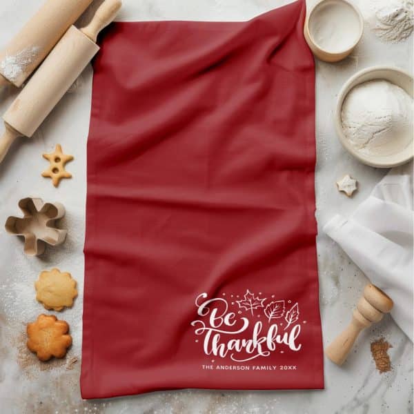 Red Kitchen Towel With &Quot;Be Thankful&Quot; In White Script And Autumn Leaves, Personalized With A Family Name And Year.