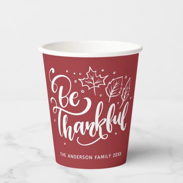 Red Paper Cup With White Lettering That Says Be Thankful And Has A Leaf Design. The Anderson Family Is Printed At The Bottom.