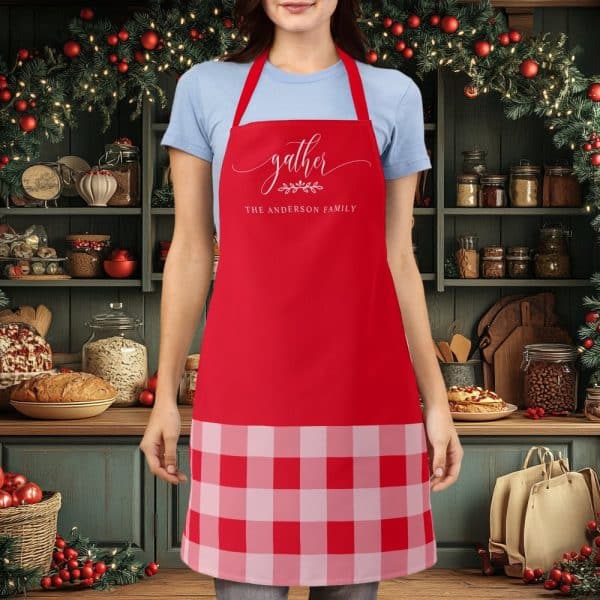 Red Apron With A Buffalo Plaid Bottom And The Words Gather, The Anderson Family In A Script Font.