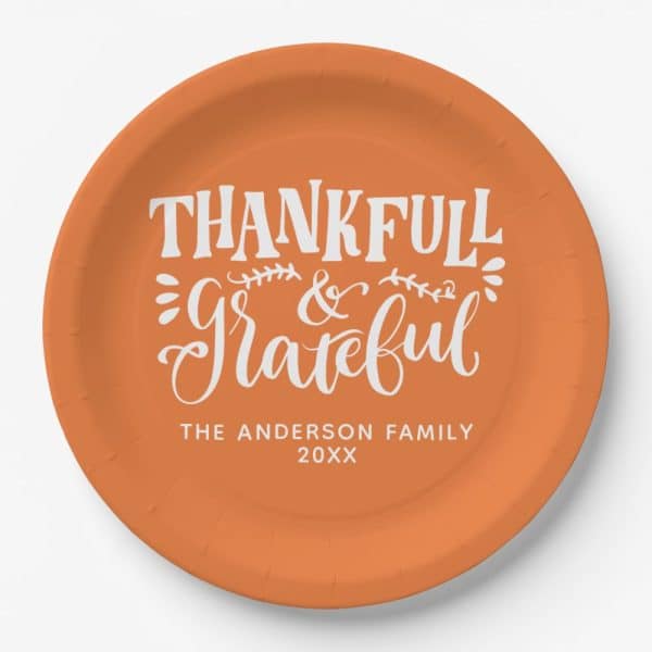 Orange Paper Plate With White Script That Says Thankful &Amp; Grateful, Along With A Family Name And Year.
