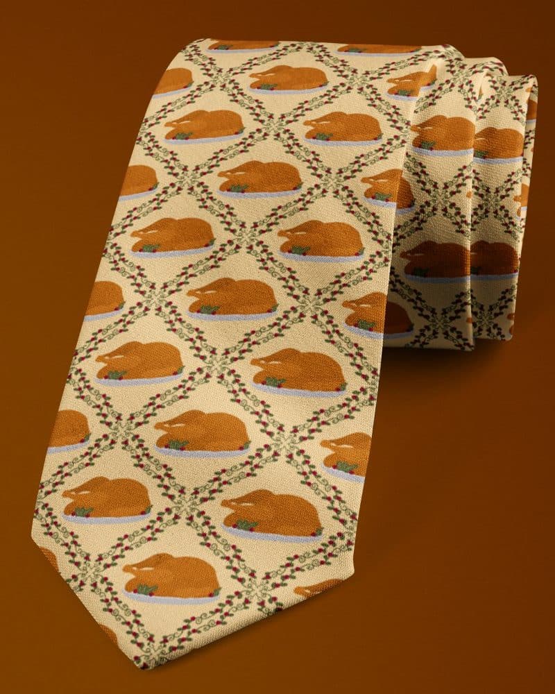 A beige necktie with a repeating pattern of roasted turkeys on platters.