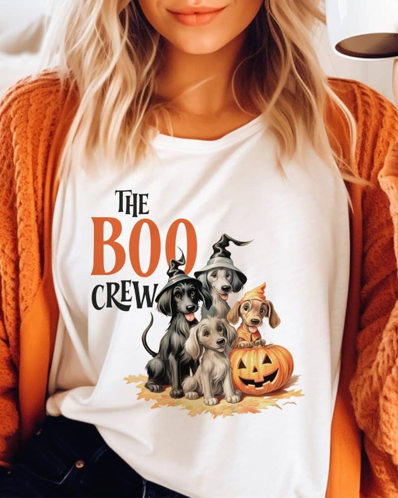 White shirt with the text The Boo Crew and an illustration of three dogs in Halloween costumes next to a pumpkin.