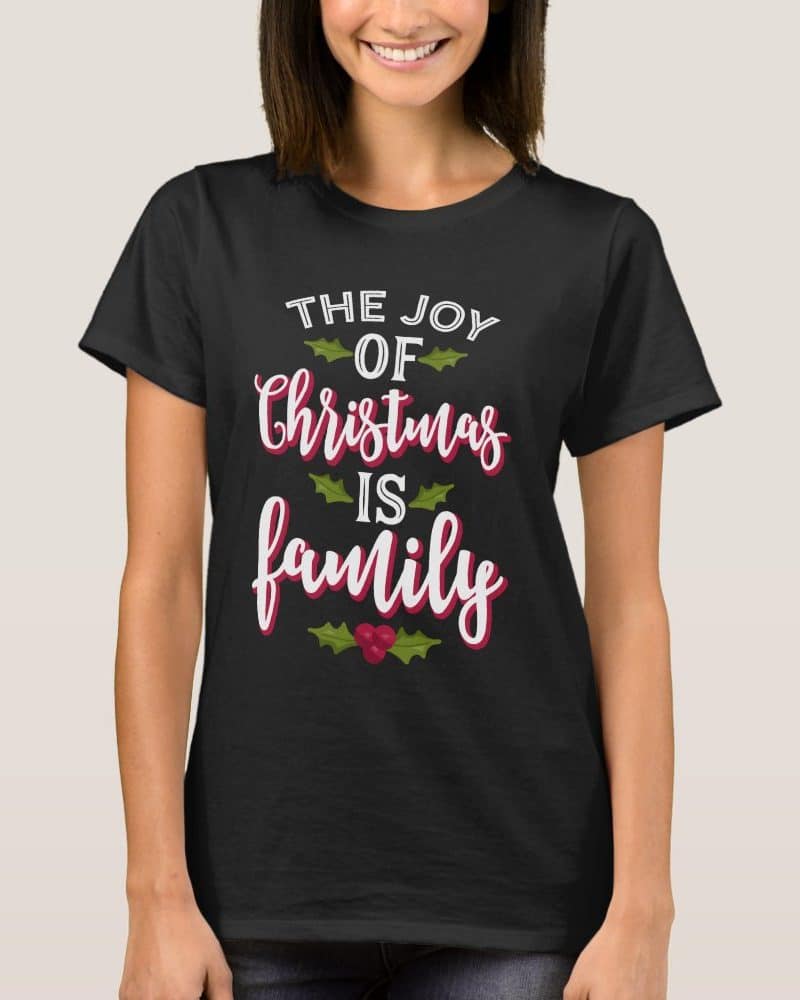 Woman wearing a black t-shirt with a Christmas design that reads, The Joy of Christmas is Family.