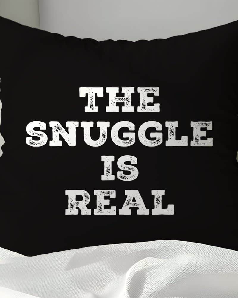 Black pillow with white text reading The Snuggle Is Real.
