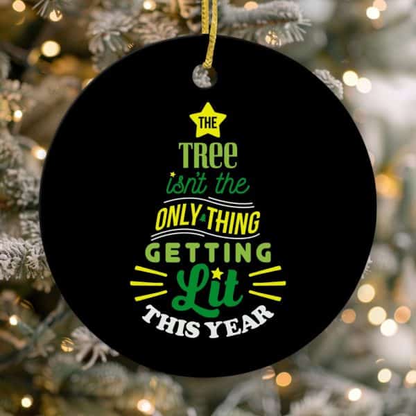 Round Black Christmas Ornament With Green And Yellow Text That Reads, The Tree Isnt The Only Thing Getting Lit This Year.