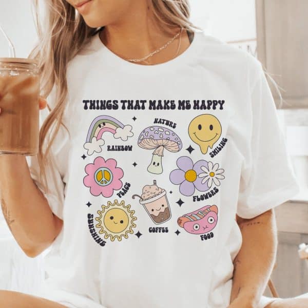 White T-Shirt With Illustrations Of Things That Make People Happy, Including A Rainbow, Flowers, Coffee, And Sunshine.