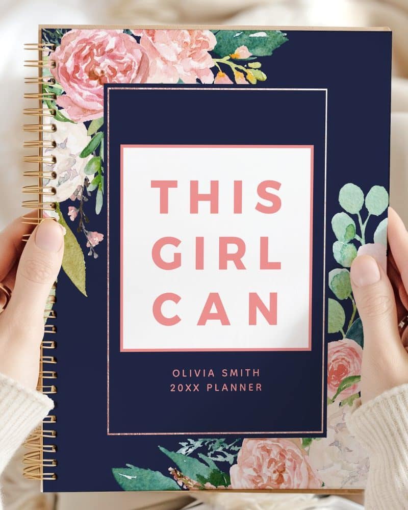 A navy planner with pink floral accents and the text This Girl Can.
