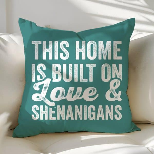 Teal Throw Pillow With White Text Reading This Home Is Built On Love &Amp; Shenanigans.