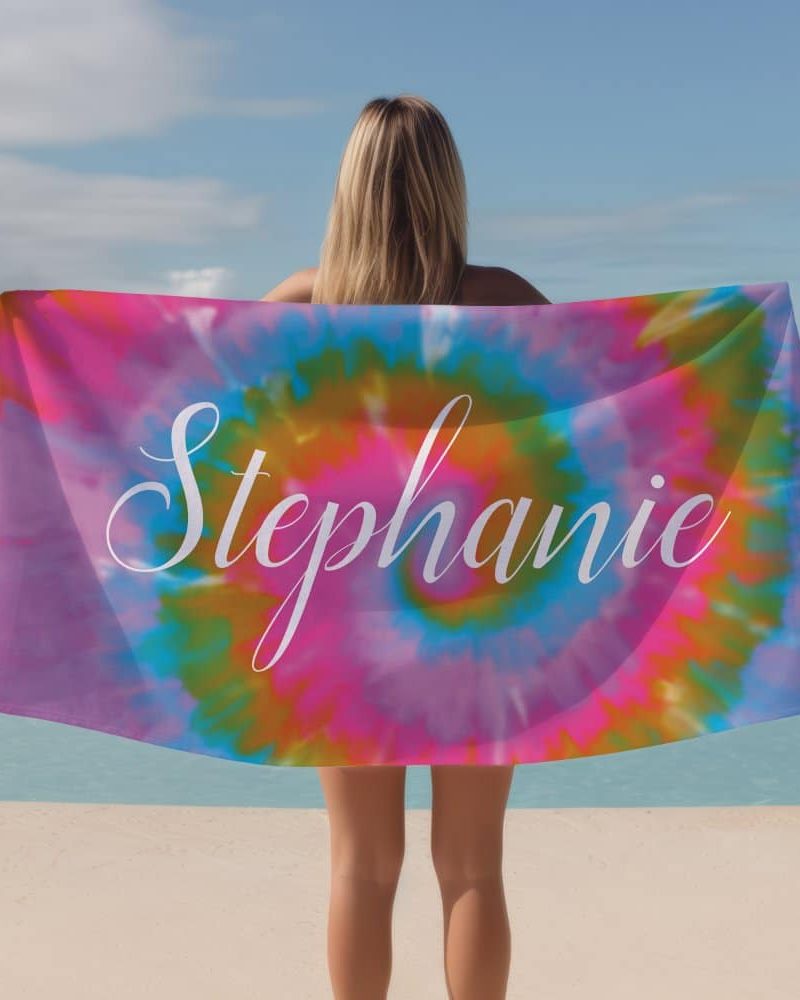 Woman holding a tie-dye beach towel with the name Stephanie on it.