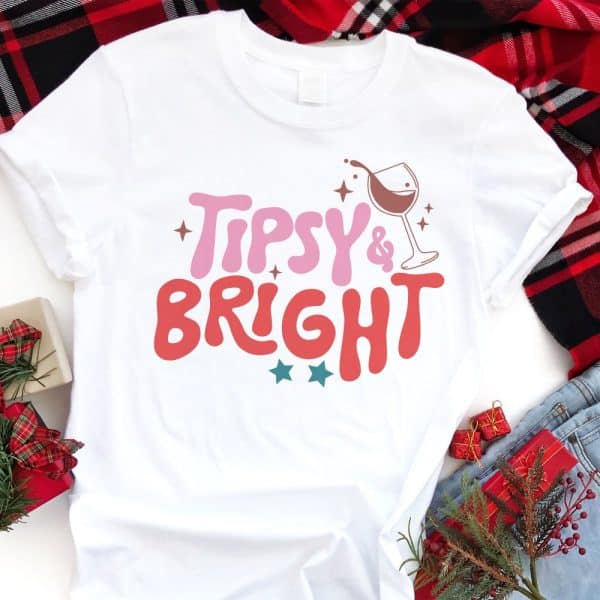 White T-Shirt With The Words Tipsy &Amp; Bright In A Retro Design, Including A Wine Glass Graphic.
