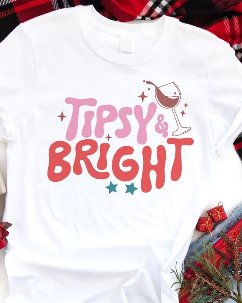 White t-shirt with the words Tipsy & Bright in a retro design, including a wine glass graphic.