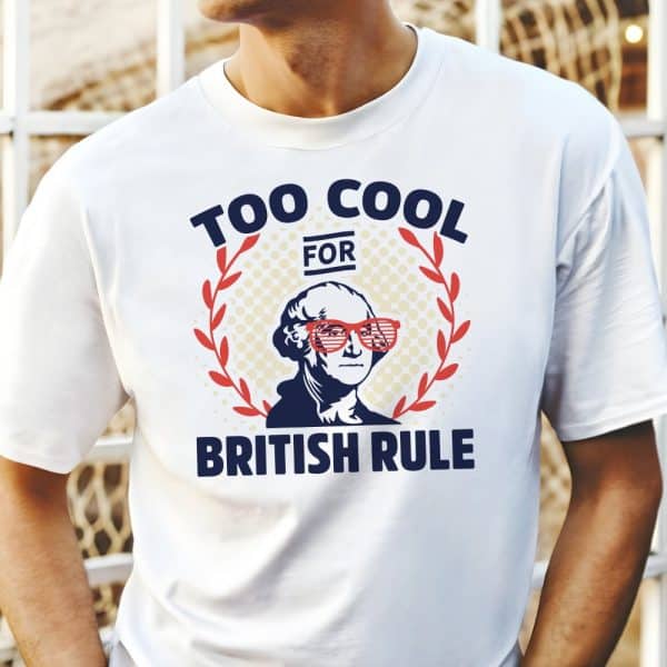 White T-Shirt With A Graphic Of George Washington Wearing Shutter Shades, Surrounded By A Laurel Wreath, And Text That Reads &Quot;Too Cool For British Rule&Quot;.