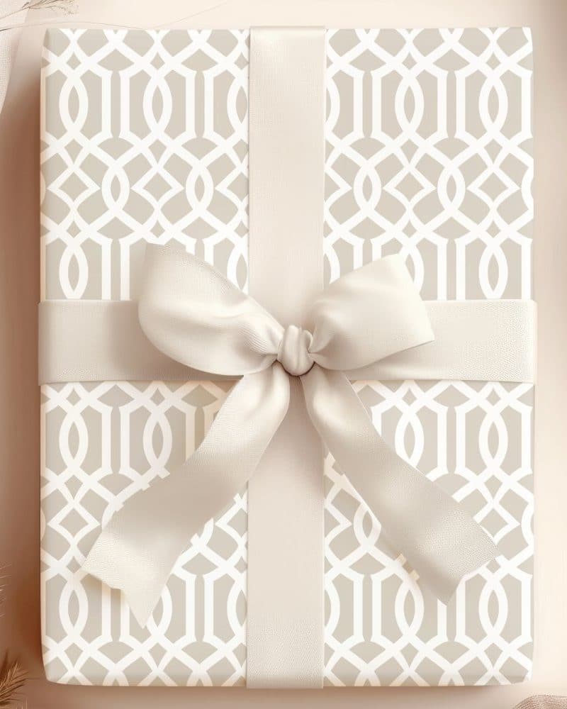 A beige gift box with a geometric pattern and a large cream-colored bow.