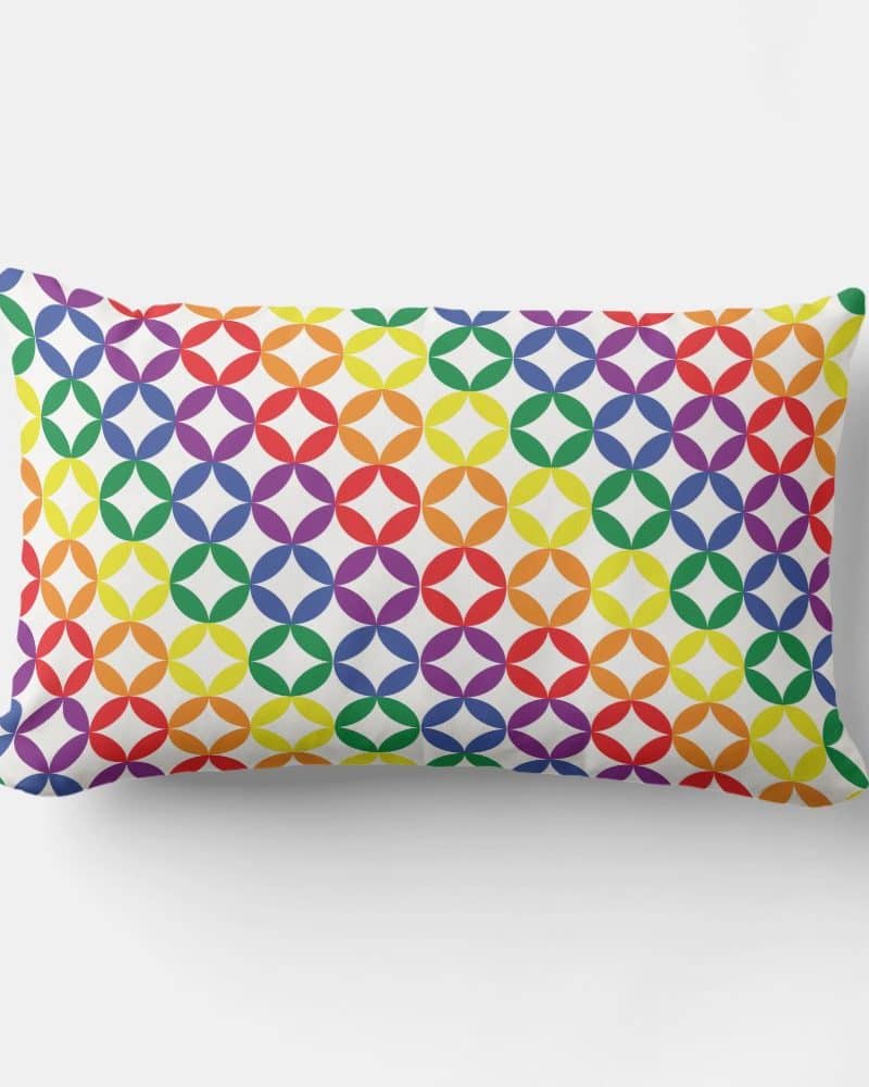 Rainbow colored pillow with a repeating geometric pattern.