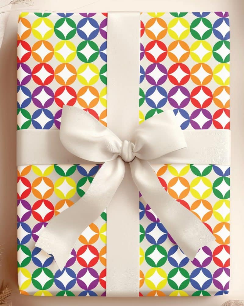 Gift wrapped in rainbow patterned paper with a cream-colored bow.