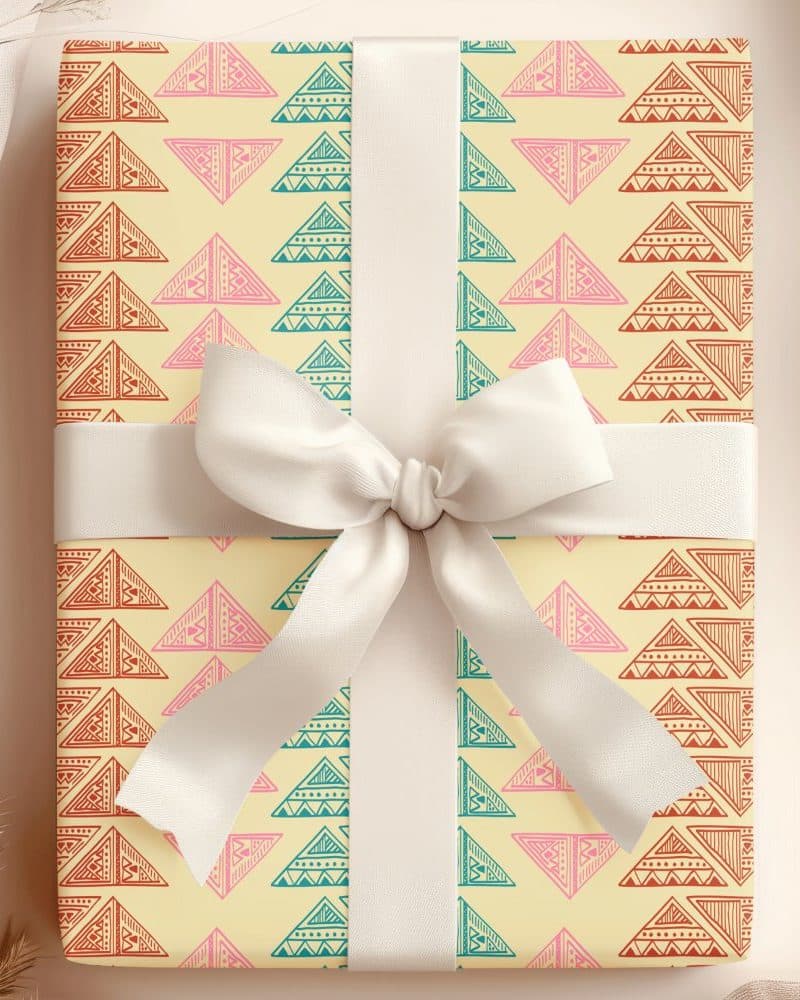 Gift box with a cream-colored background and a repeating pattern of colorful triangles. A large white bow is tied on top.