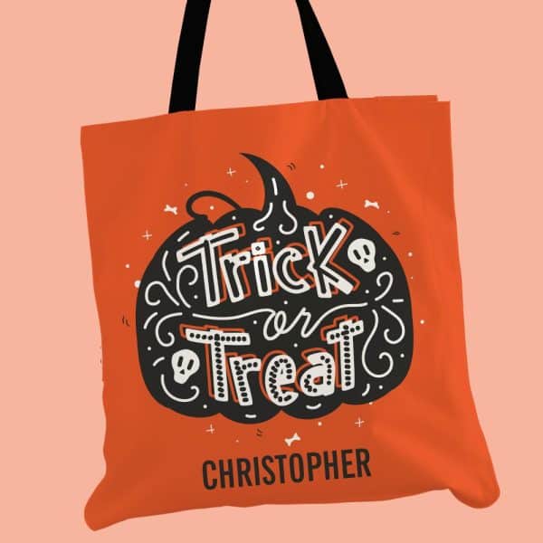 Orange Halloween Tote Bag With Black And White Trick Or Treat Design In The Shape Of A Pumpkin And The Name Christopher Below.
