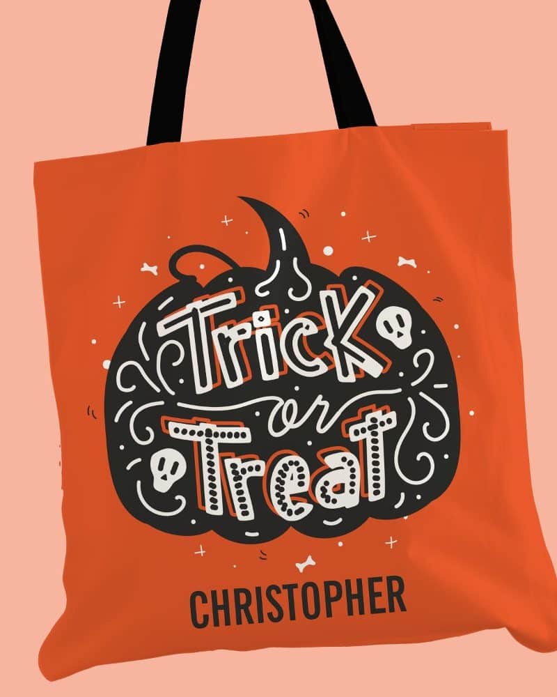 Orange Halloween tote bag with black and white Trick or Treat design in the shape of a pumpkin and the name Christopher below.