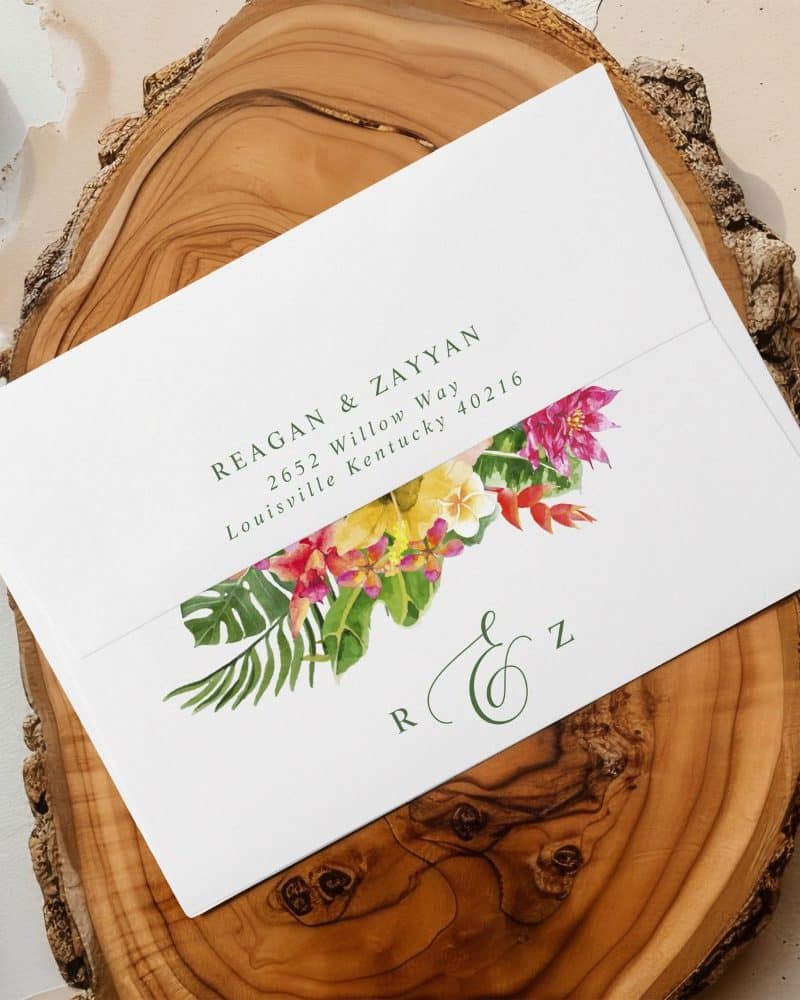 Wedding invitation envelope with tropical floral design and recipient's address.