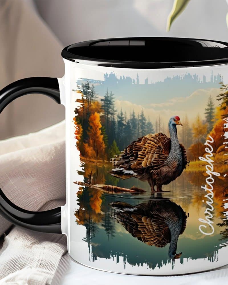Black-handled mug with a colorful image of a turkey reflected in a calm body of water, set against an autumnal forest backdrop. The name Christopher is visible on the mug.