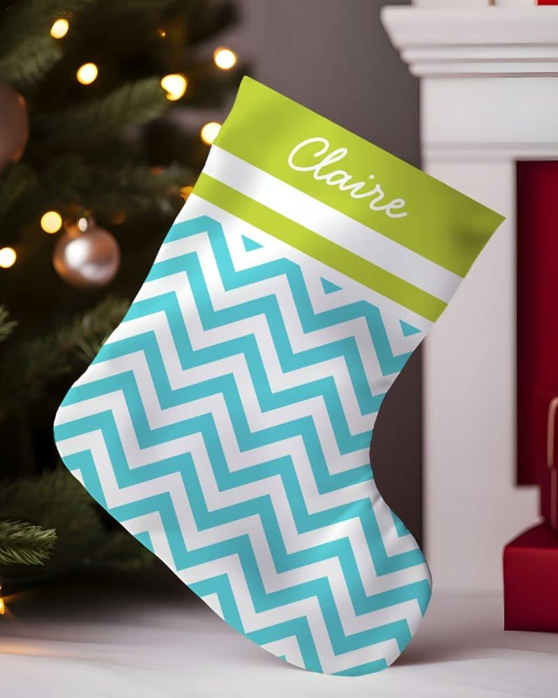 A teal and white chevron patterned Christmas stocking with the name Claire on a lime green band.