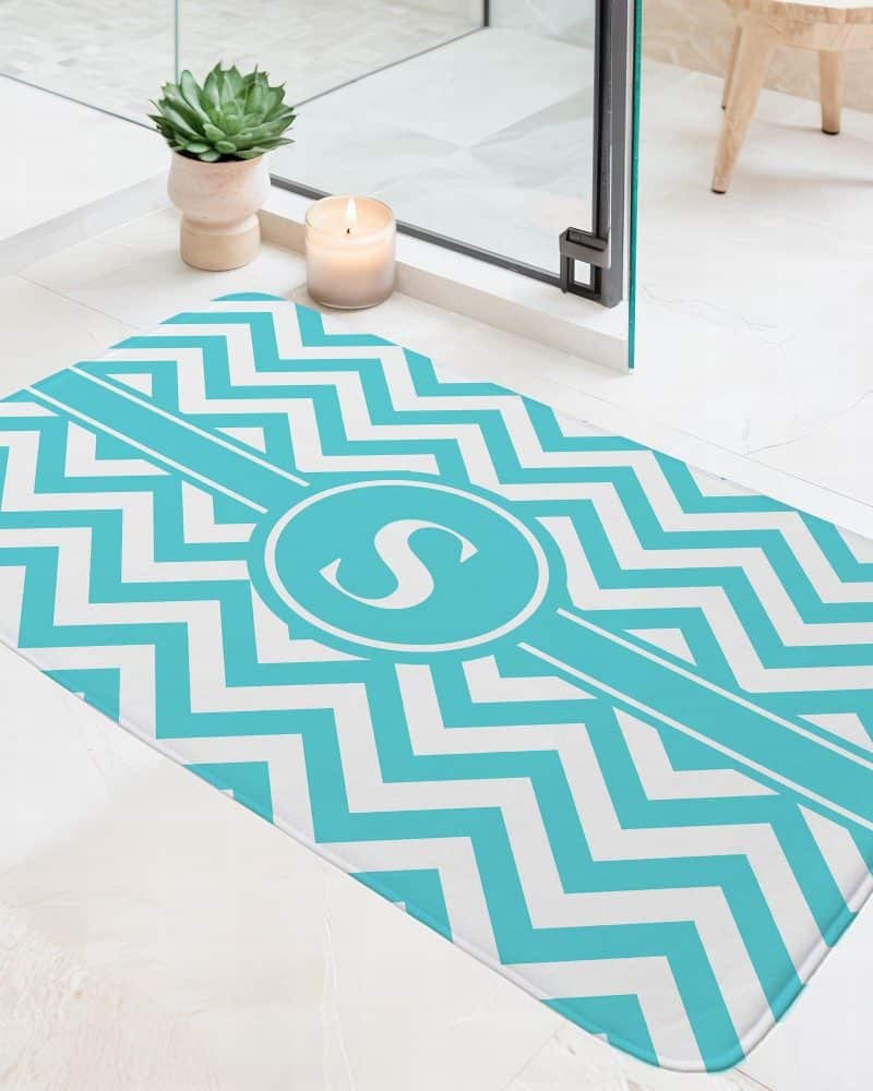 Teal and white chevron patterned bath mat with a monogrammed S in a circle.
