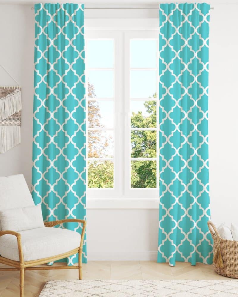 Teal curtains with a white quatrefoil pattern hang on a window.