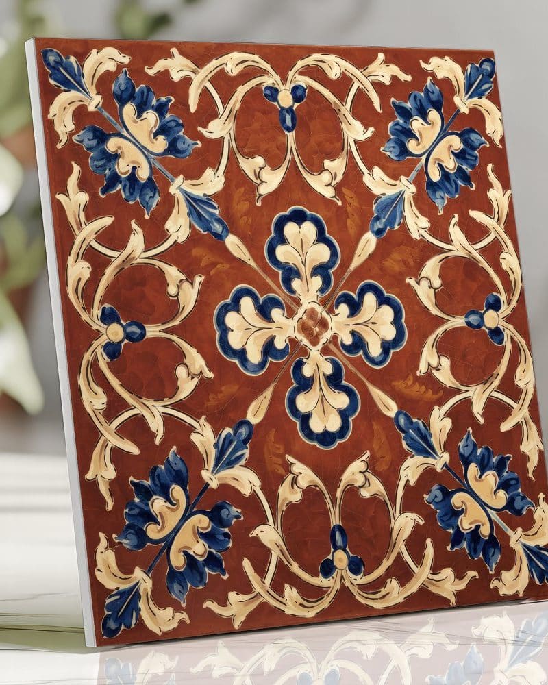 Ornate square tile with a brown background and blue and beige floral pattern.