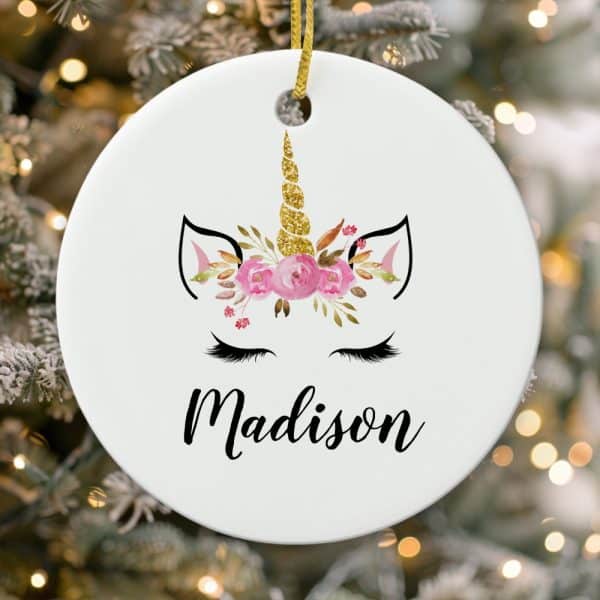 Round White Christmas Ornament Featuring A Unicorn Face With Pink Flowers And Gold Glitter Horn, Personalized With The Name Madison.