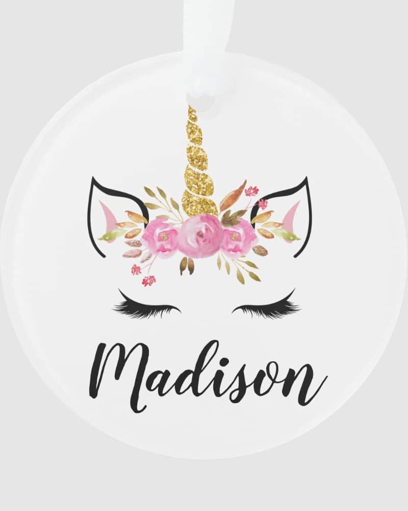 Round ornament featuring a unicorn face with a gold glitter horn and pink flowers, personalized with the name Madison.