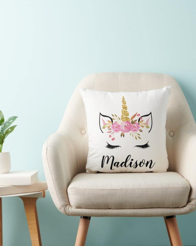 A cream-colored pillow with a floral unicorn design and the name Madison.