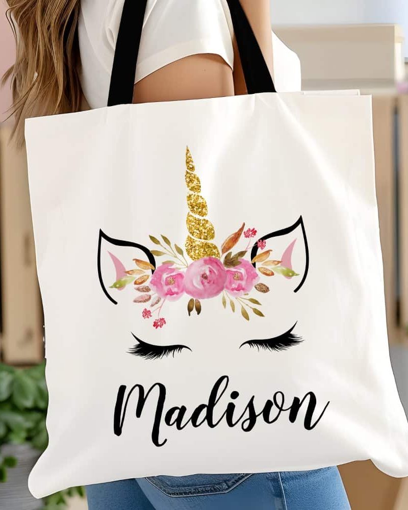 White tote bag with a gold glitter unicorn horn and pink flowers, and the name Madison printed on it.