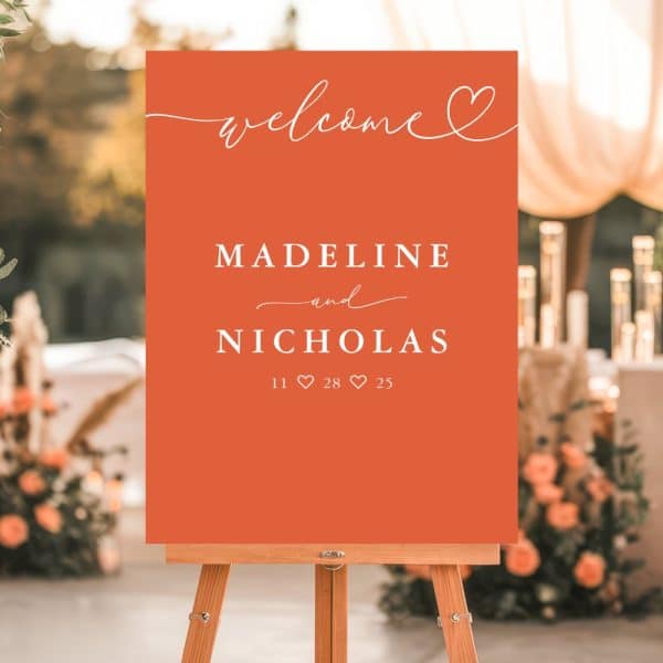 An Orange Wedding Welcome Sign On An Easel Displaying Madeline And Nicholas'S Names And Wedding Date.