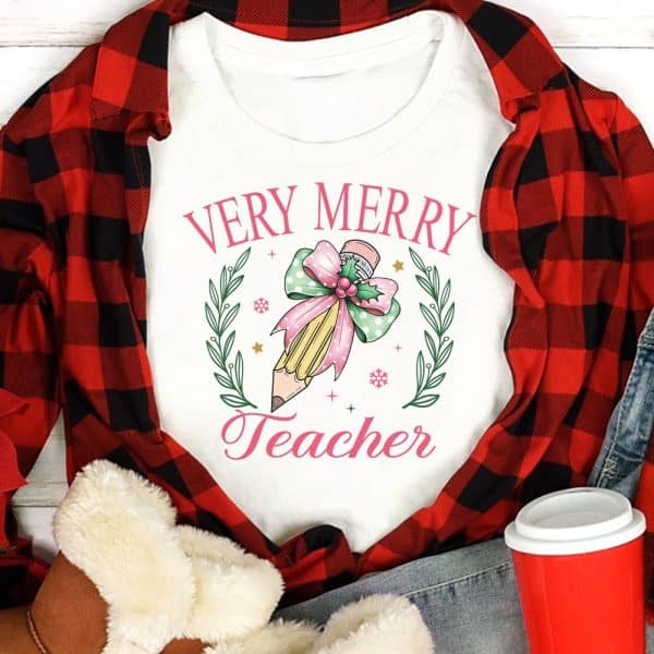 White Shirt With Very Merry Teacher Design Featuring A Pencil With A Pink Bow And Holly.