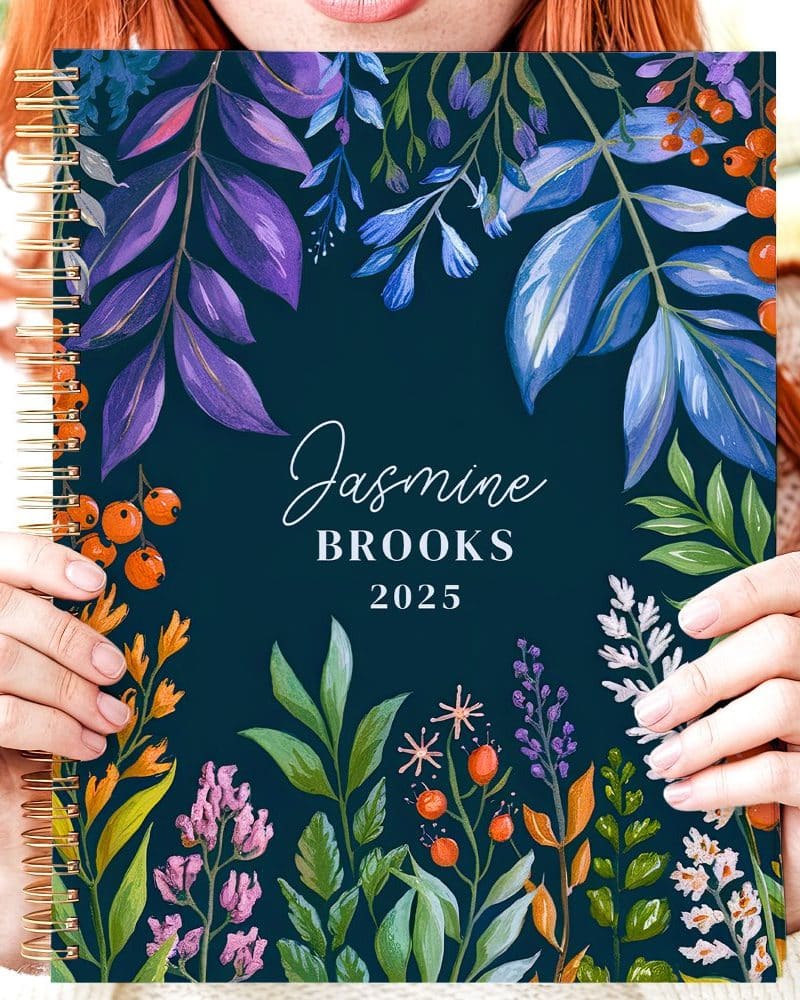 Person holding a 2025 spiral-bound planner with a floral design and their name, Jasmine Brooks.