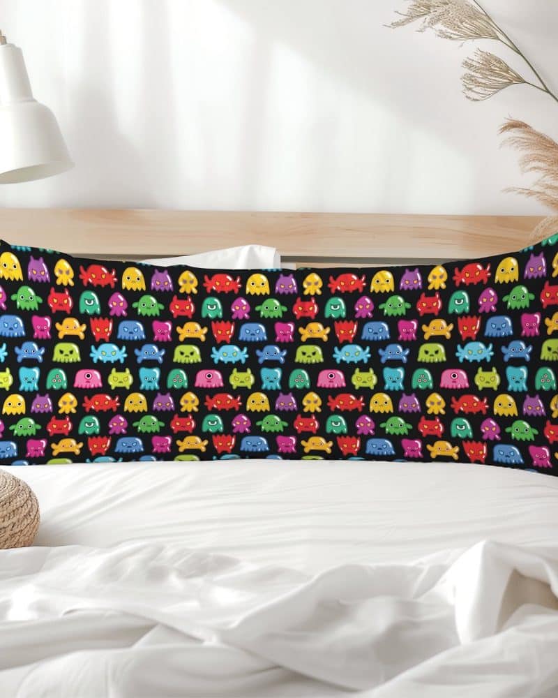 A black rectangular pillow with a repeating pattern of colorful cartoon monsters.