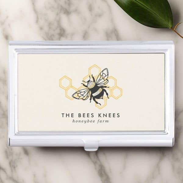 Silver Business Card Holder With A Cream Colored Card Featuring A Black Bumblebee Illustration Centered On A Honeycomb Graphic. The Text The Bees Knees Honeybee Farm Is Below The Image.