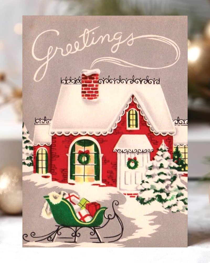 A vintage Christmas card depicting a snow-covered red house with a sleigh full of presents in front.