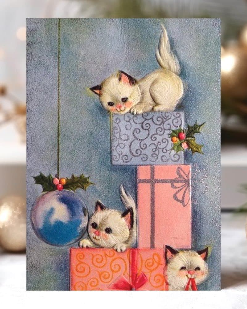 Three kittens playing on a stack of Christmas presents.