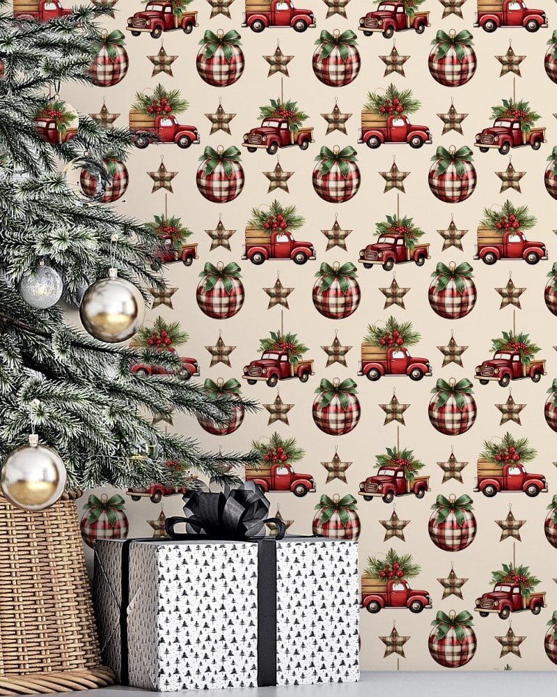Christmas tree next to a gift in front of a wall featuring a repeating pattern of red plaid ornaments and vintage red trucks carrying Christmas trees.