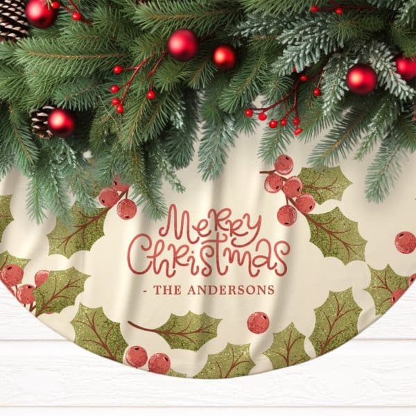 A Cream-Colored Christmas Tree Skirt With A Merry Christmas Message And The Andersons Family Name, Decorated With Holly Leaves And Berries, Is Topped With A Garland Of Pine Boughs And Red Ornaments.