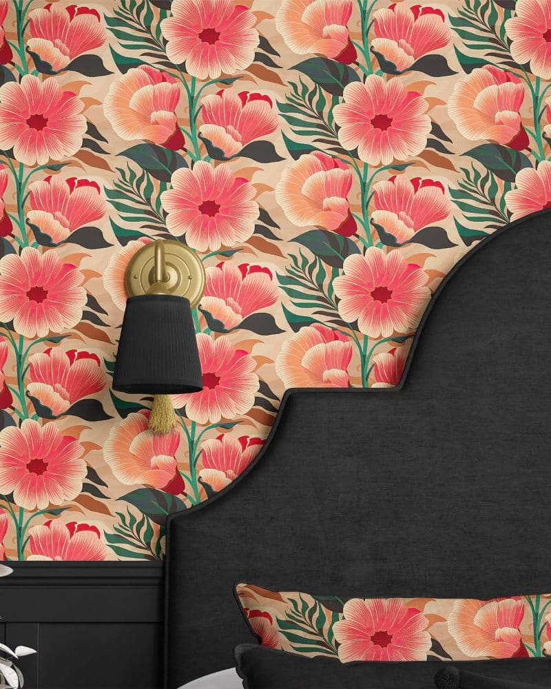 A black headboard against a wall covered in a large-scale coral and peach floral wallpaper.