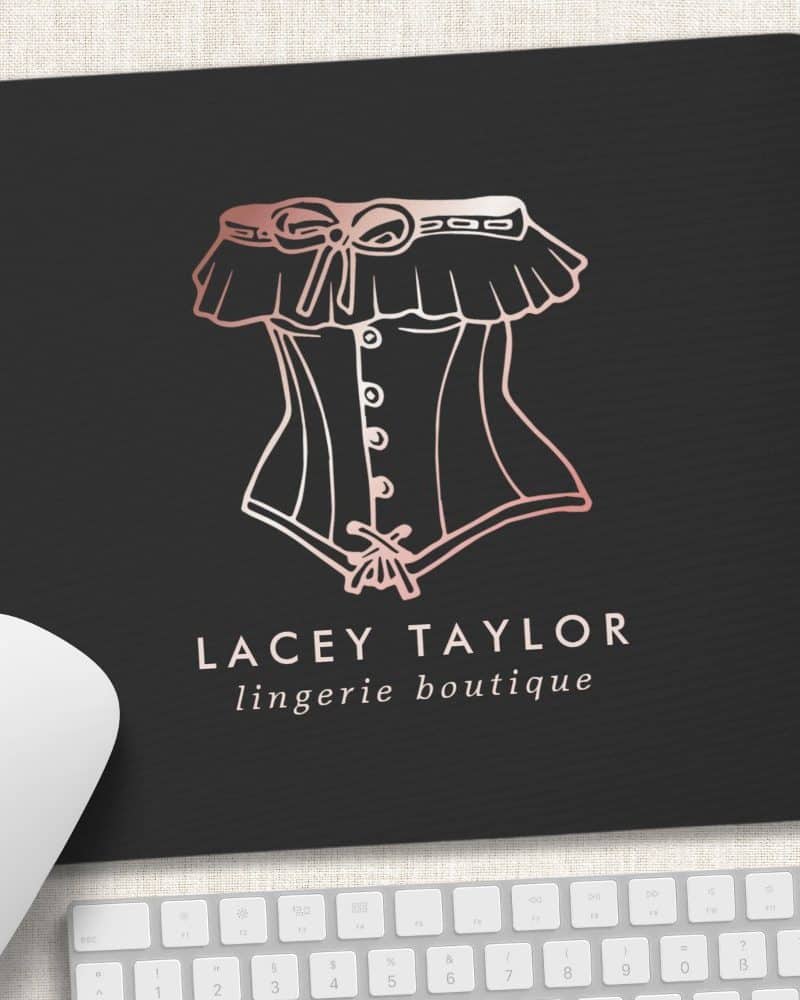Black mousepad with a rose gold outline drawing of a corset and the text Lacey Taylor lingerie boutique.